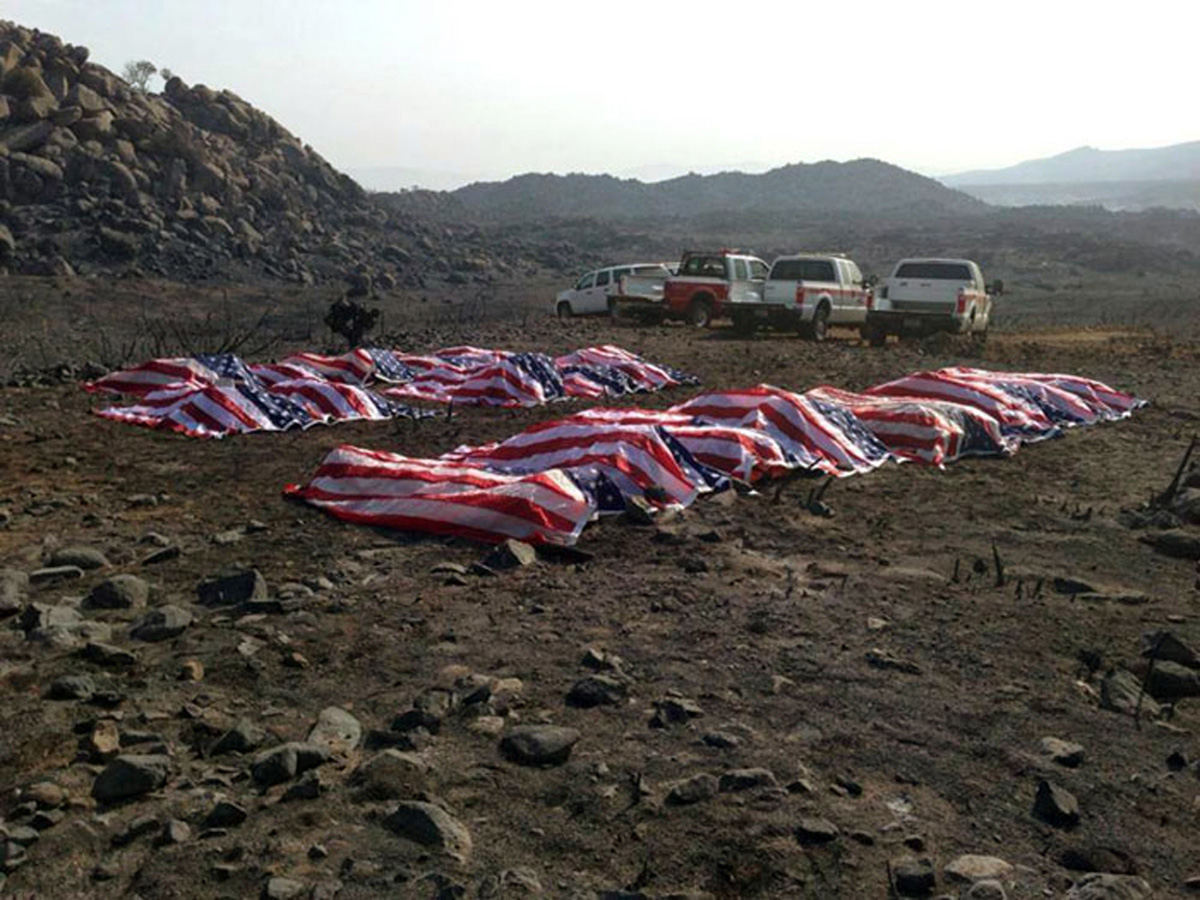 This photo that appeared anonymously on Facebook on Thursday, July 4, 2013, shows what officials confirmed to The Associated Press, as the 19 dead firefighters draped in American flags by Yavapai County Sheriff Scott Mascher, shortly after they were found dead near Prescott, Ariz., on June 30, 2013. Several media outlets, including the Arizona Republic and USA Today, published the photo on Friday, July 5, 2013. Nineteen members of the Granite Mountain Hotshot crew died Sunday, June 30, 2013 fighting the Yarnell Hills Fire, about 40 miles southwest of Prescott. (AP Photo)