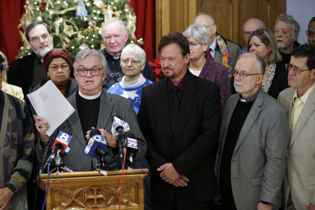 The Rev. Herb Snyder, at podium, holds up a letter of support for the Rev. Frank Schaefer, center right, a United Methodist clergyman convicted of breaking church law for officiating at his son's same-sex wedding, during a news conference, Monday, Dec. 16, 2013, at the Arch Street United Methodist Church in Philadelphia. Schaefer plans to defy a church order to surrender his credentials for performing a same-sex wedding. (AP Photo/Matt Rourke)