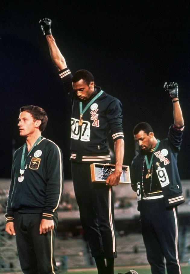 Extending gloved hands skyward in racial protest, U.S. athletes Tommie Smith, center, and John Carlos stare downward during the playing of the Star Spangled Banner after Smith received the gold and Carlos the bronze for the 200 meter run at the Summer Olympic Games in Mexico City on Oct. 16, 1968. (AP Photo/FILE)