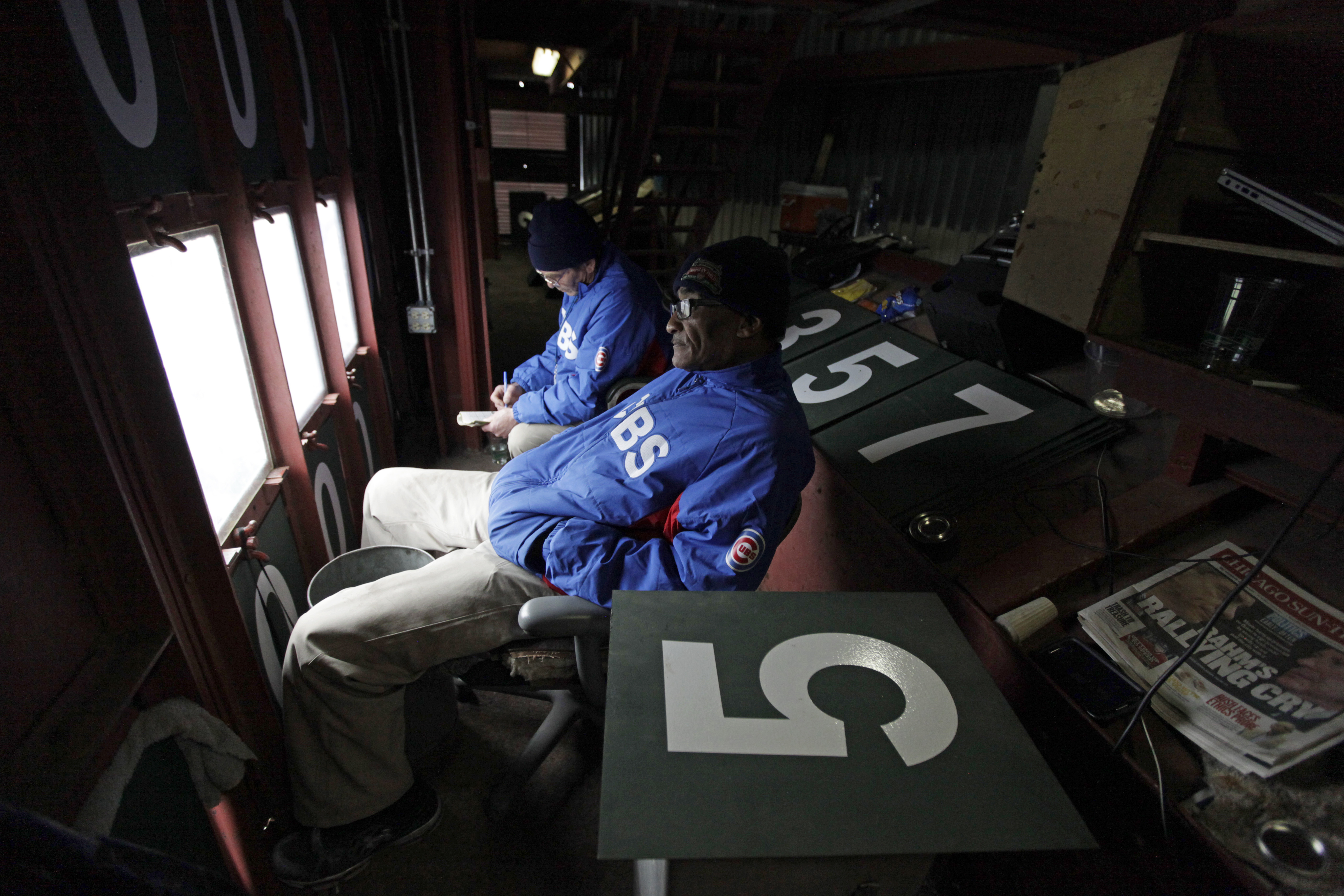 Scoreboard operators Fred Washington, right, and Brian Helmus look out to the field from inside of the scoreboard. (AP Photo/Kiichiro Sato)