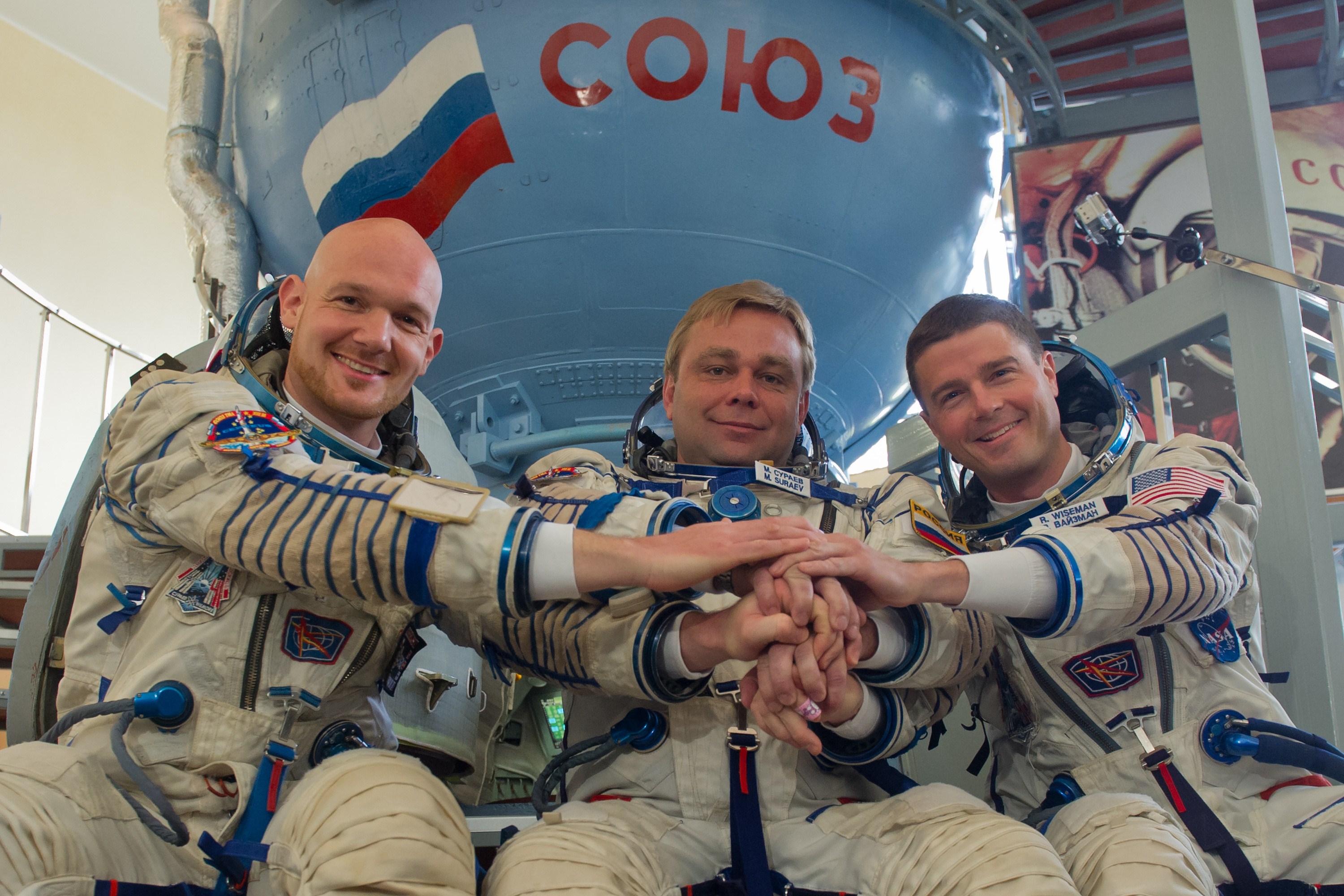 More European than American: Crew members of the 40/41 expedition to the International Space Station, European Space Agency's German astronaut Alexander Gerst (L), Russian cosmonaut Maxim Suraev (C) and US NASA astronaut Gregory Wiseman (R) join their  hands in front of a mock-up of a Soyuz TMA spacecraft at the Gagarin Cosmonauts' Training Centre in Star City, outside Moscow, on May 7, 2014. The crew is to take off from Kazakhstan's Baikonur cosmodrome to the ISS on May 28. Photo: AFP/Getty Images.