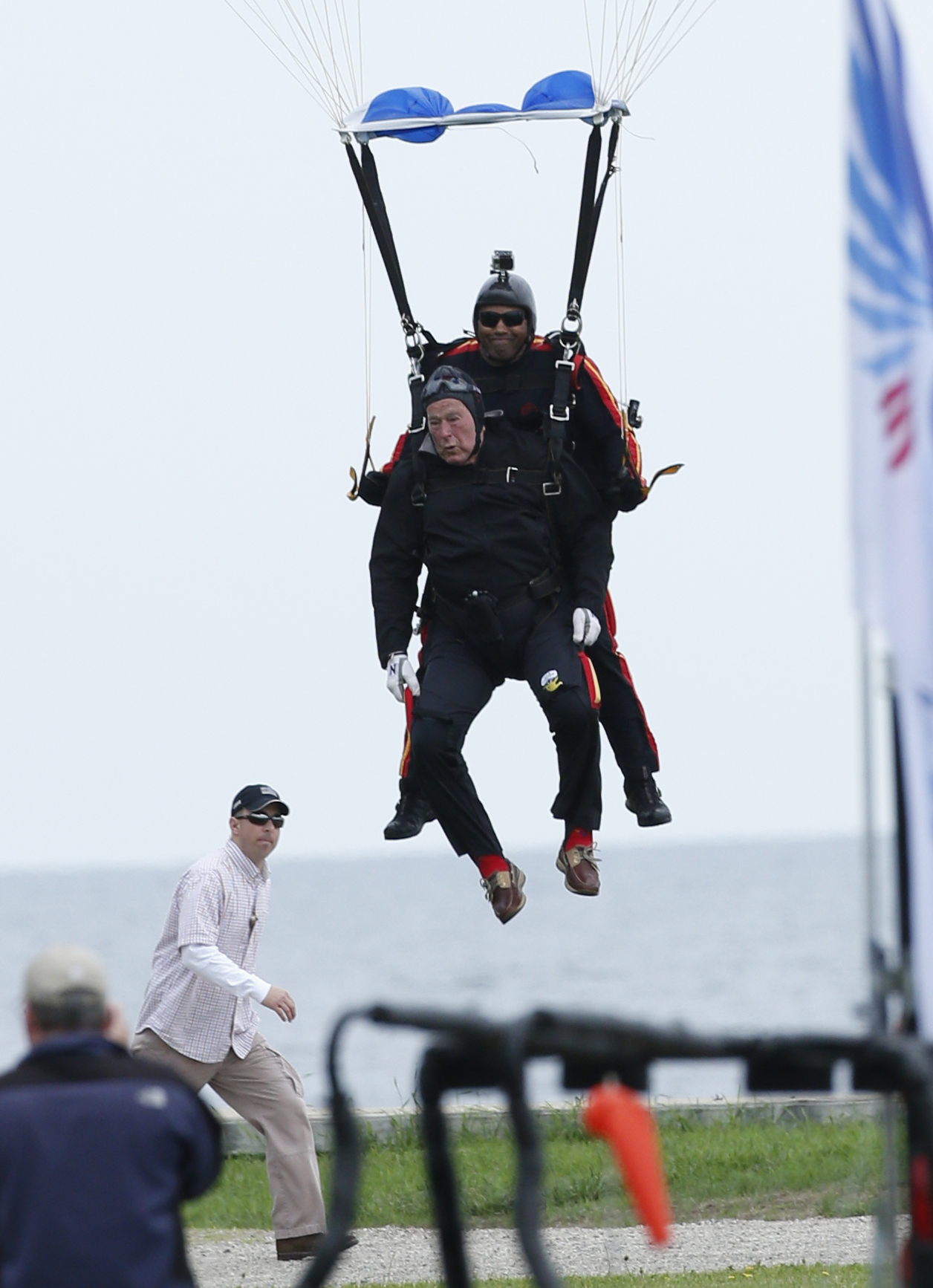 Former President George H.W. Bush, strapped to Sgt. 1st Class Mike Elliott, a retired member of the Army's Golden Knights parachute team, prepare to land on the lawn at St. Anne's Episcopal Church while celebrating Bush's 90th birthday in Kennebunkport, Maine, Thursday, June 12, 2014. Photo: Robert F. Bukaty/Associated Press.