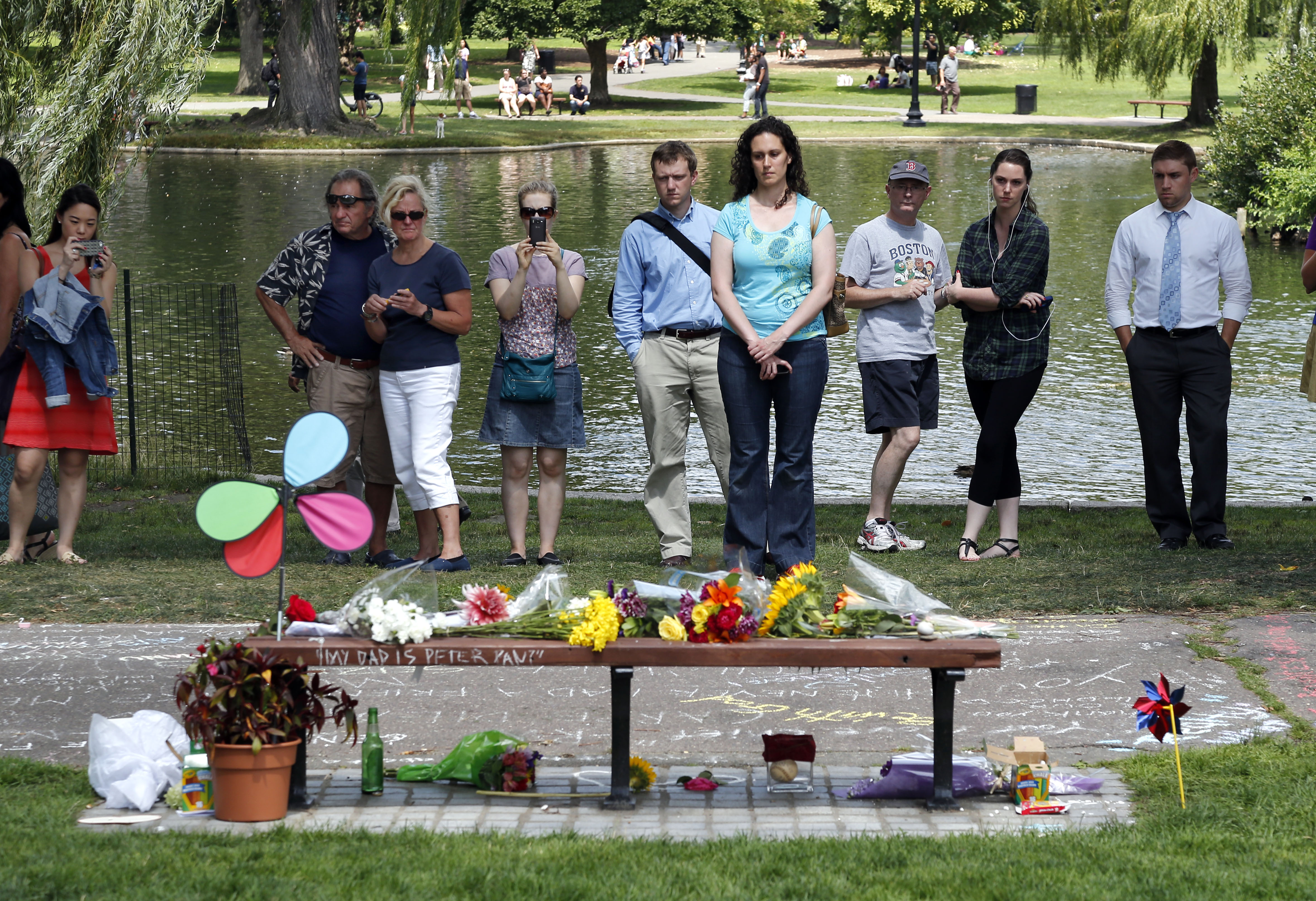 People pause by a bench at Boston's Public Garden, Tuesday, Aug. 12, 2014, where a small memorial has sprung up at the place where Robin Williams filmed a scene during the movie, "Good Will Hunting." Williams, 63, died at his San Francisco Bay Area home Monday in an apparent suicide.  Photo: Elise Amendola/Associated Press
