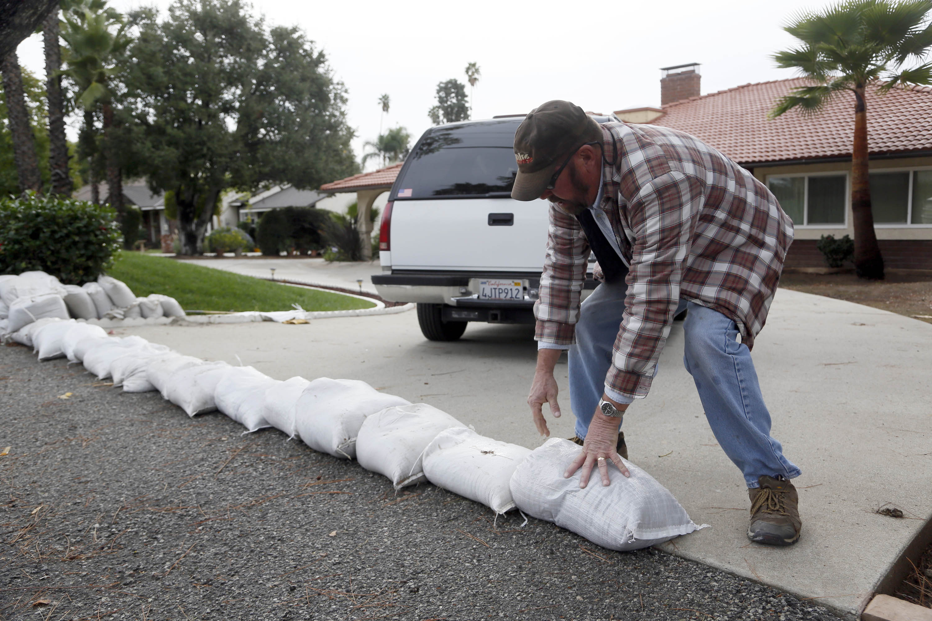 Richard Pope places sand bags along his driveway to protect his home from an expected storm in Glendora, Calif. on Monday, Dec.1, 2014.  California is bracing for the arrival of a new, more powerful Pacific storm following a weekend of scattered rain, showers and snow. The National Weather Service says a low-pressure system off the coast will draw a plume of subtropical moisture northward into the state beginning on Tuesday. (AP Photo/Nick Ut)