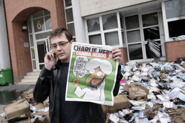 The Charlie Hebdo's publisher, known only as Charb, uses his cell phone as he shows a special edition of French satirical magazine Charlie Hebdo on November 2, 2011 in Paris.  Photo: Alexander Klein/AFP/Getty Images.