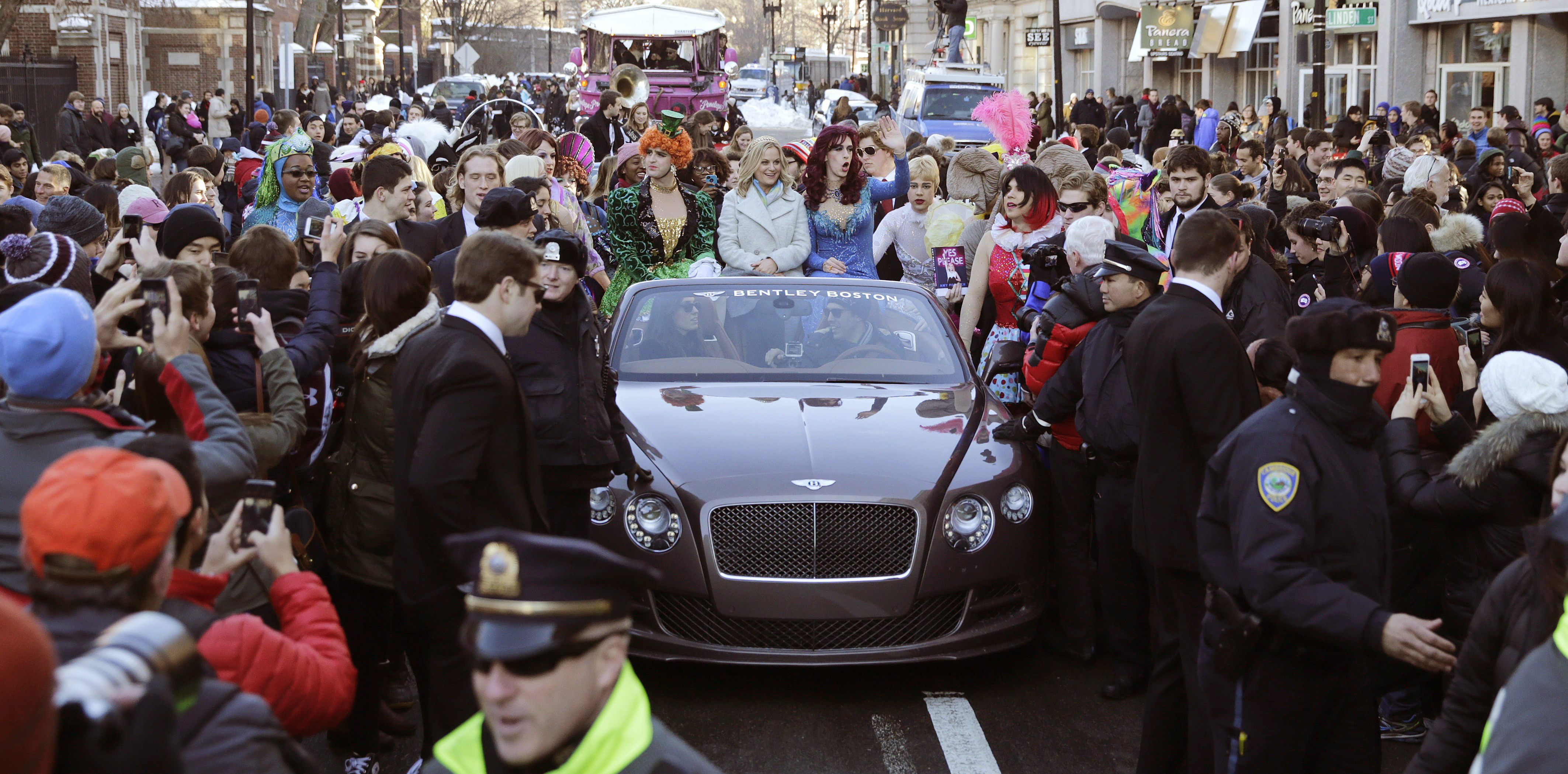 Actress Amy Poehler, center, sits with Jason Hellerstein, left, and Sam Clark, who are dressed in drag, as she rides in a convertible through Harvard Square in Cambridge, Mass., Thursday Jan. 29, 2015. Poehler was honored as "Woman of the Year" by the Hasty Pudding Theatricals at Harvard University. (AP Photo/Charles Krupa)