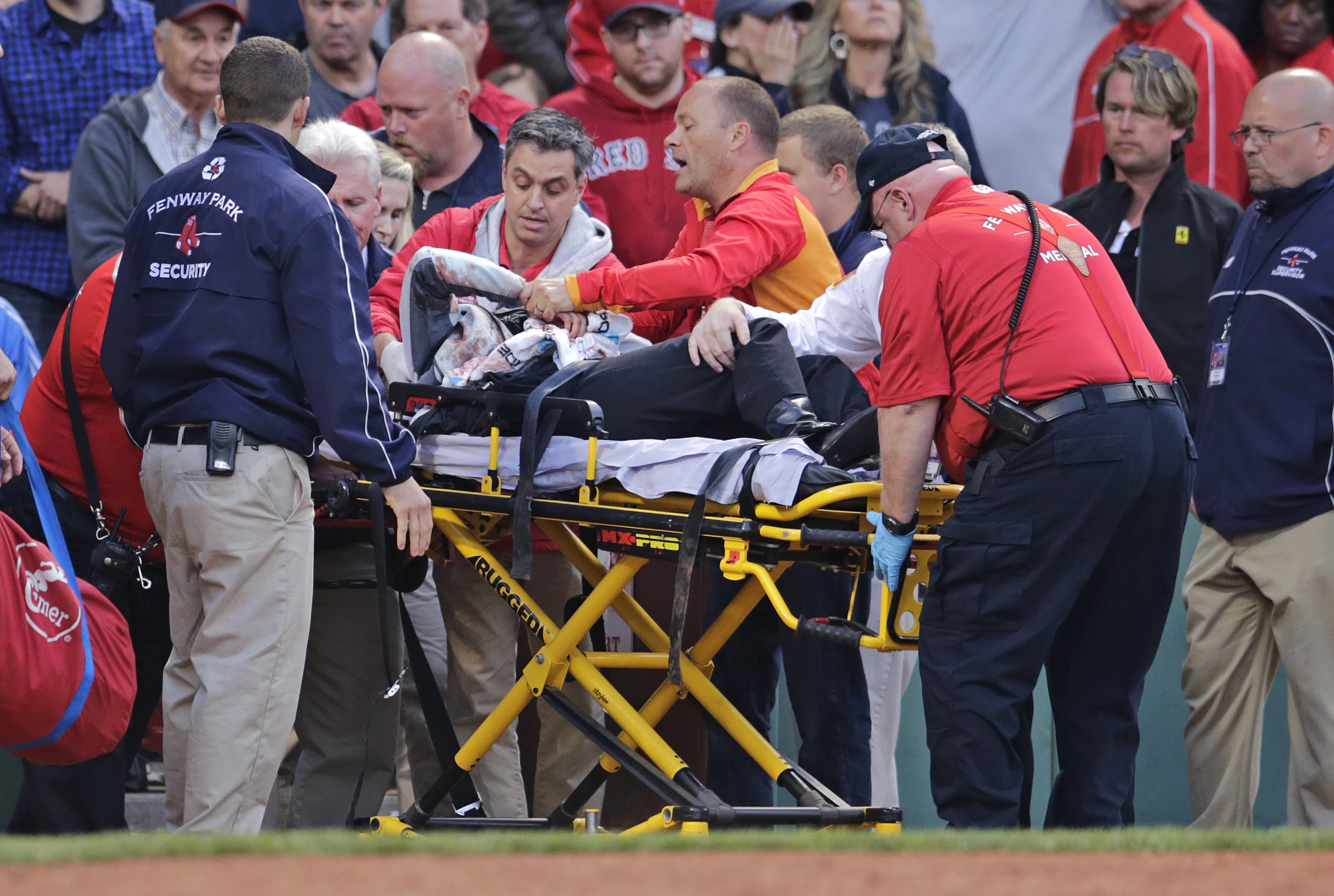 A fan, who was accidentally hit in the head with a broken bat by Oakland Athletics' Brett Lawrie, is helped from the stands during a baseball game against the Boston Red Sox at Fenway Park in Boston, Friday, June 5, 2015.  The game was stopped while they wheeled her down the first base line. (AP Photo/Charles Krupa)