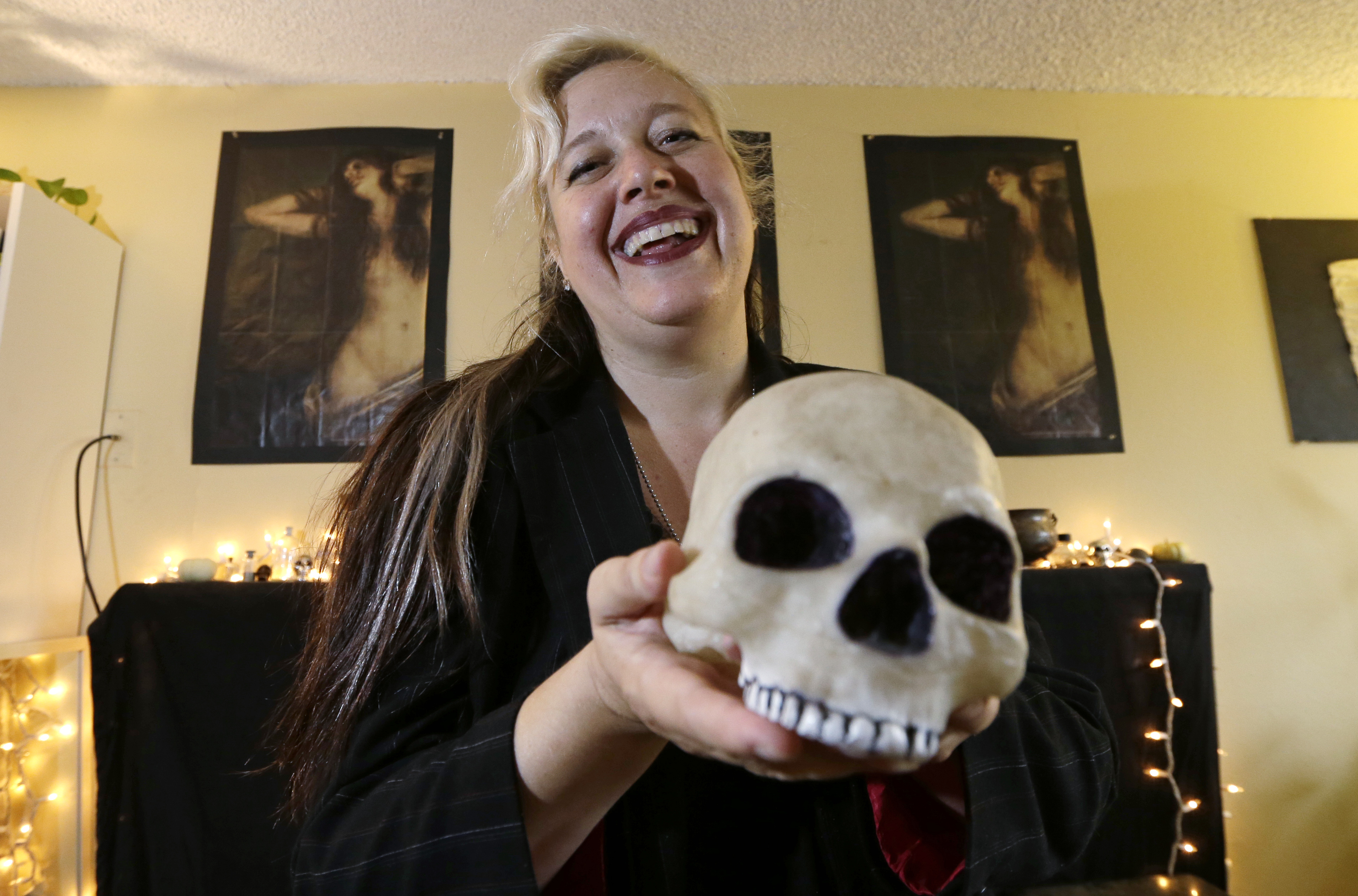 Lilith Starr, chapter head of The Satanic Temple of Seattle, holds a plastic skull while being photographed in her home Wednesday, Oct. 28, 2015, in Seattle. At the invitation of the Bremerton High School senior class president, Starr says that her group of self-described Satanists will attend the school's football game Thursday to protest a decision by a Christian coach to continue praying at the 50-yard line after games. (AP Photo/Elaine Thompson)