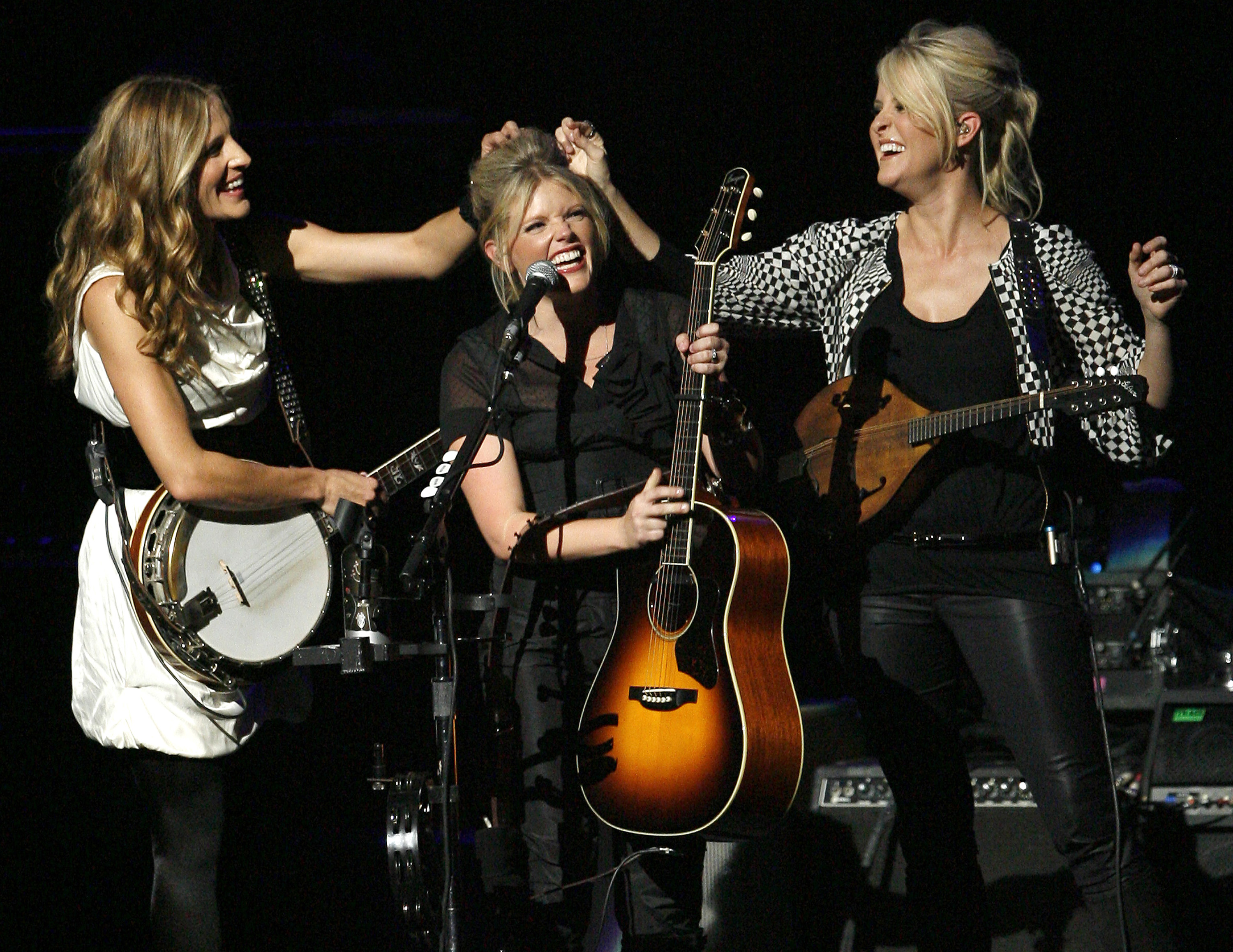  In this Oct. 18, 2007 file photo, Emily Robison, left, and Martie Maguire, right, adjust Natalie Maines' hair as the Dixie Chicks perform in Los Angeles. (AP Photo/Gus Ruelas, file)