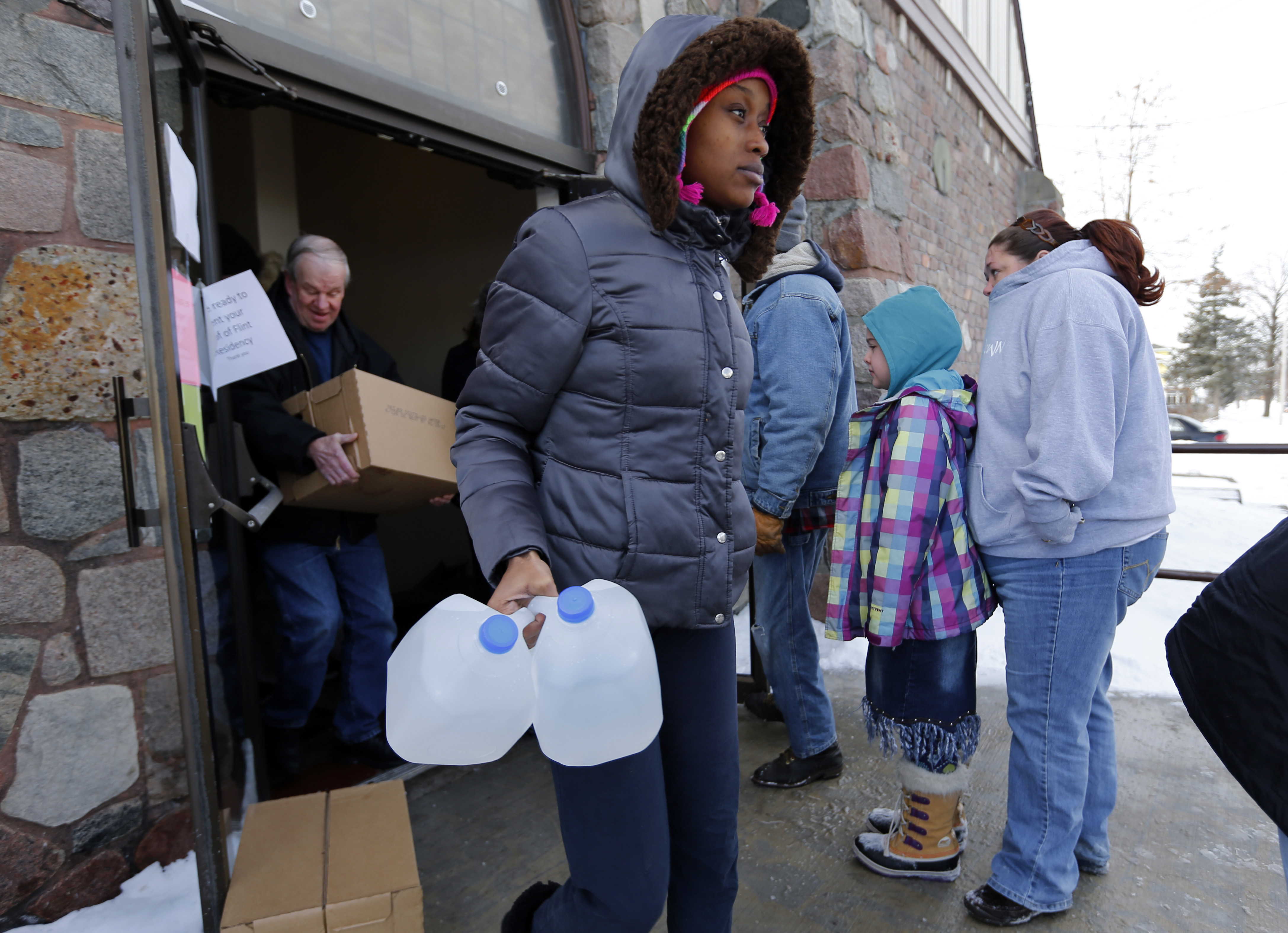 In this February 2015 photo, Genetha Campbell carries free water being distributed at the Lincoln Park United Methodist Church in Flint, Mich. (AP Photo/Paul Sancya)