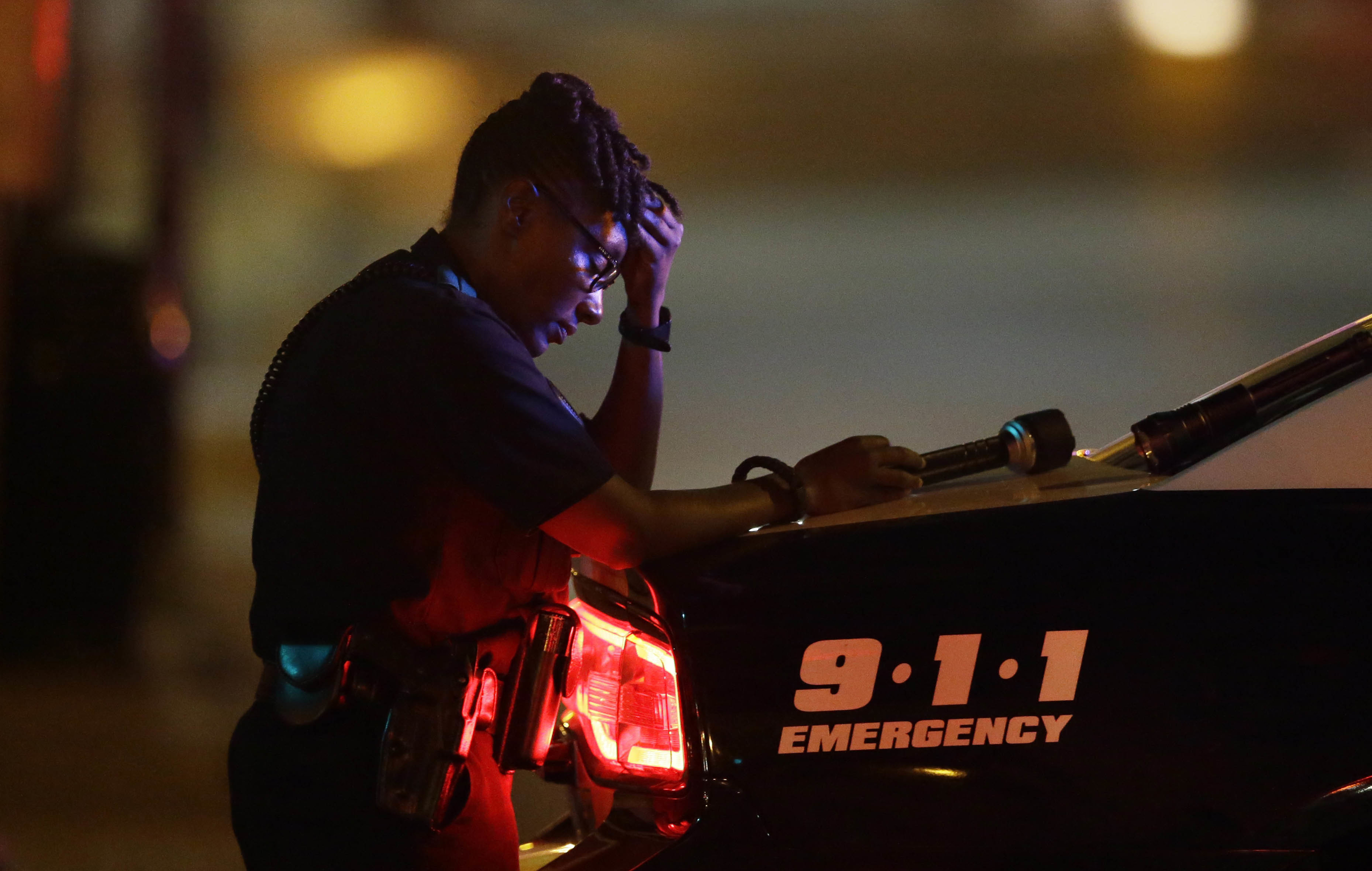 A Dallas police officer, who did not want to be identified, takes a moment as she guards an intersection in the early morning after a shooting in downtown Dallas, Friday, July 8, 2016.  AP Photo/LM Otero.