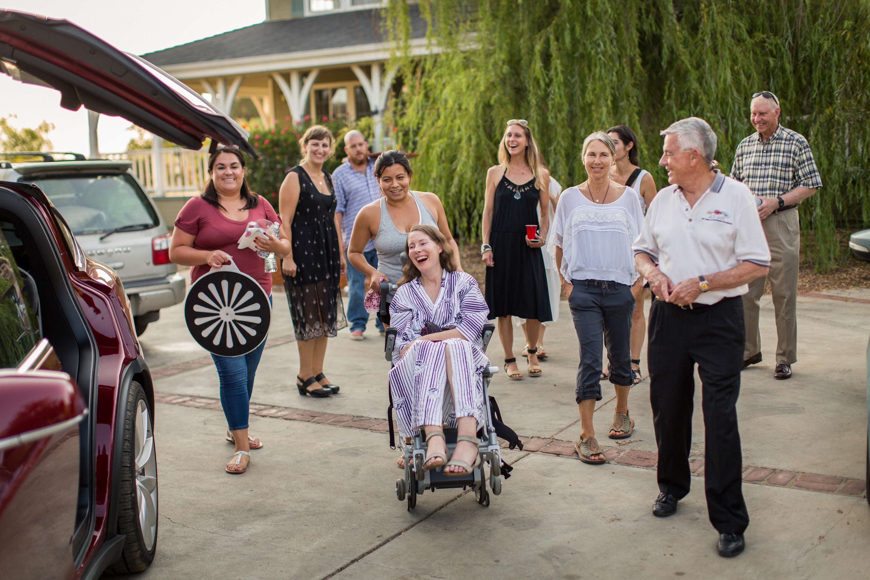 This July 24, 2016 photo provided by Niels Alpert, Betsy Davis, center, is accompanied by friends and family for her first ride in a friends new Tesla to a hillside to end her life during a "Right To Die Party" in Ojai, Calif.  In early July, Davis emailed her closest friends and family to invite them to a two-day celebration, telling them: "These circumstances are unlike any party you have attended before, requiring emotional stamina, centeredness, and openness.  And one rule: No crying. " The 41-year-old woman diagnosed with ALS,  held the party to say goodbye before becoming one of the first California residents to take life-ending drugs under a new law that gave such an option to the terminally ill. (Niels Alpert via AP)