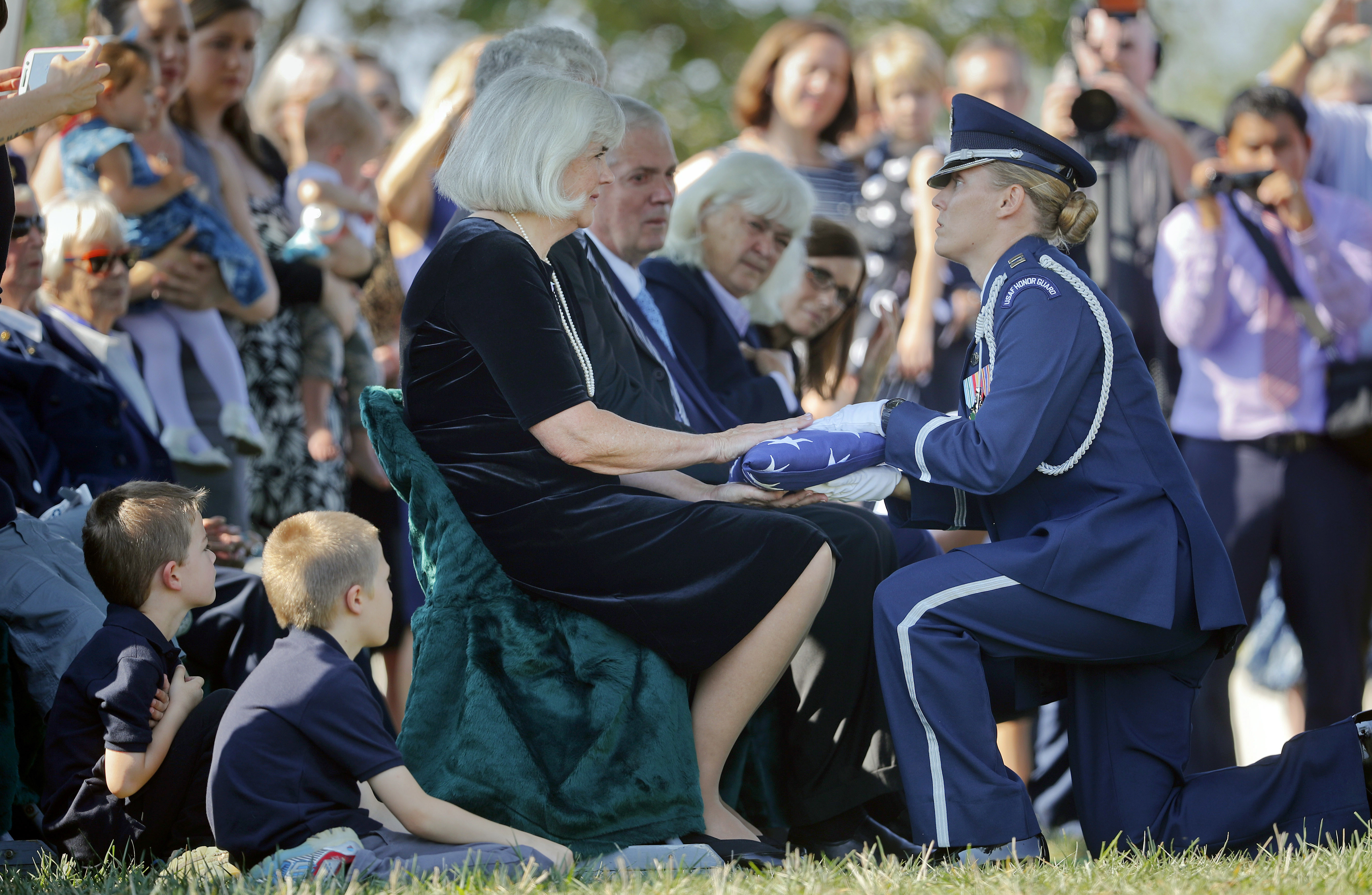 Air Force Capt. Jennifer Lee, right, kneels as she presents an American flag to Terry Harmon, center seated, daughter of World War II pilot Elaine Danforth Harmon, during burial services, Wednesday, Sept. 7, 2016 at Arlington National Cemetery in Arlington, Va. It took an act of Congress, but Harmon was finally laid to rest on at Arlington National Cemetery, she died last year at age 95. She was one of the Women Airforce Service Pilots (WASP), a group of women who flew military aircraft on noncombat missions during World War II so that men were freed up for combat. (AP Photo/Pablo Martinez Monsivais)