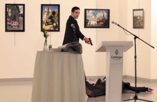 An unnamed gunman shouts after shooting the Russian Ambassador to Turkey, Andrei Karlov, at a photo gallery in Ankara, Turkey, Monday, Dec. 19, 2016.  A gunman in a suit and tie shouted slogans about Syria's civil war after he killed Russia's ambassador to Turkey in front of stunned onlookers at a photo exhibition in the Turkish capital on Monday, according to an Associated Press photographer who witnessed the shooting. Police later killed the assailant, Turkish station NTV reported. (AP Photo/Burhan Ozbilici)