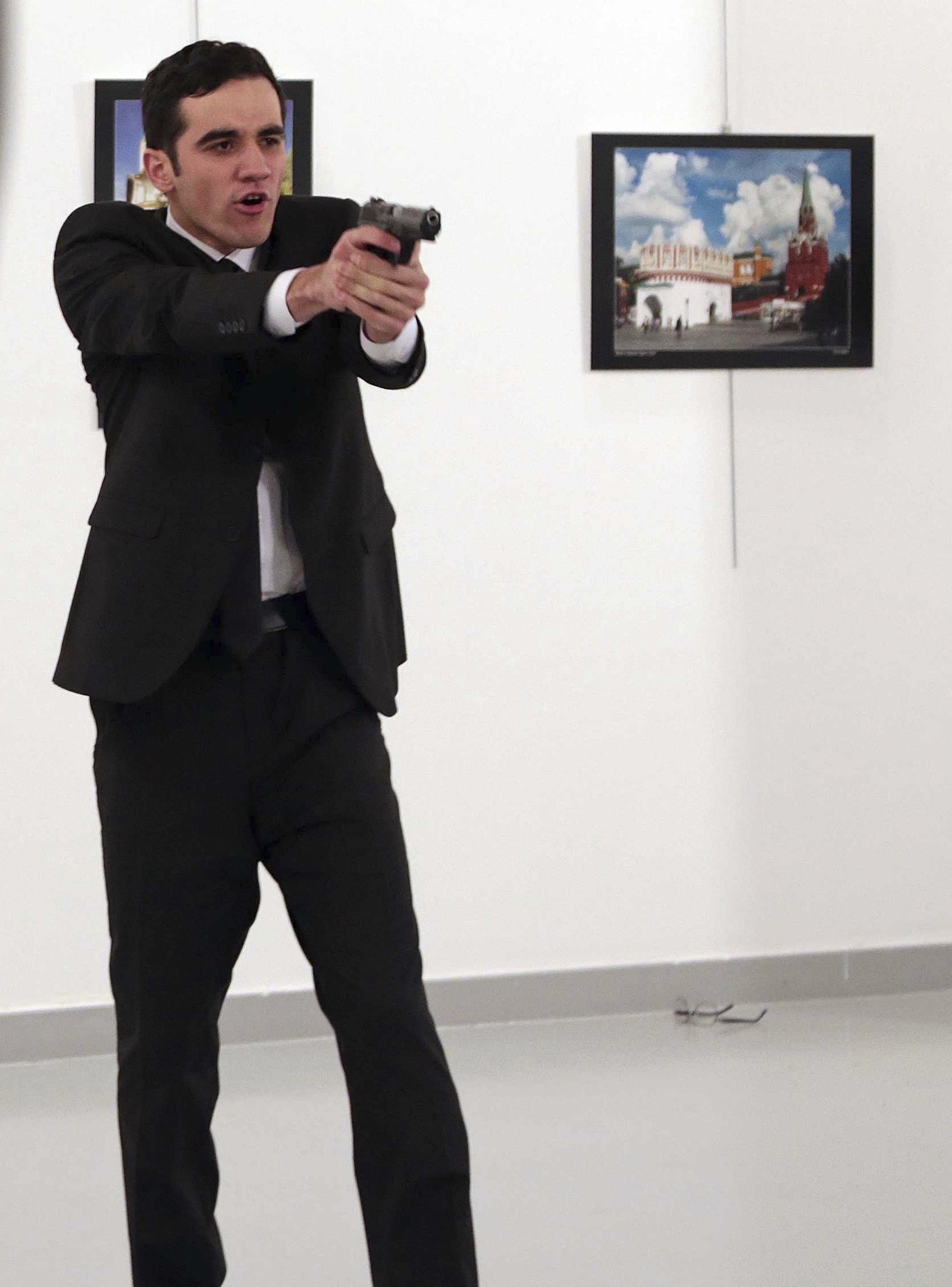 An unnamed gunman points his gun, after shooting the Russian Ambassador to Turkey, Andrei Karlov, at a photo gallery in Ankara, Turkey, Monday, Dec. 19, 2016. A gunman in a suit and tie shouted slogans about Syria's civil war after he killed Russia's ambassador to Turkey in front of stunned onlookers at a photo exhibition in the Turkish capital on Monday, according to an Associated Press photographer who witnessed the shooting. Police later killed the assailant, Turkish station NTV reported. (AP Photo/Burhan Ozbilici)