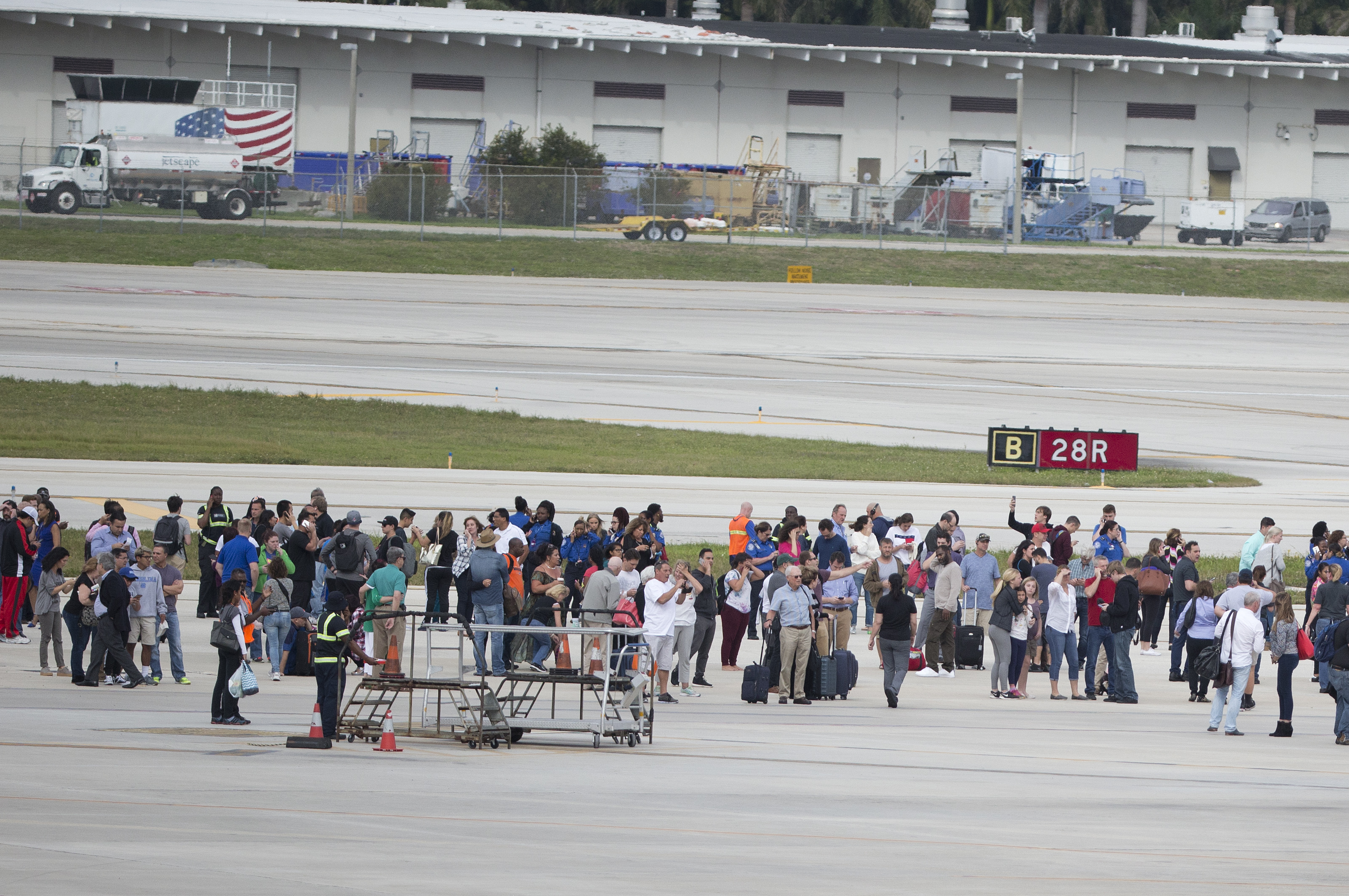 People stand on the tarmac at Fort Lauderdale–Hollywood International Airport, after a gunman opened fire in the baggage claim area at the airport killing several people and wounding others before being taken into custody Friday, Jan. 6, 2017, in Fort Lauderdale, Fla. (AP Photo/Wilfredo Lee)