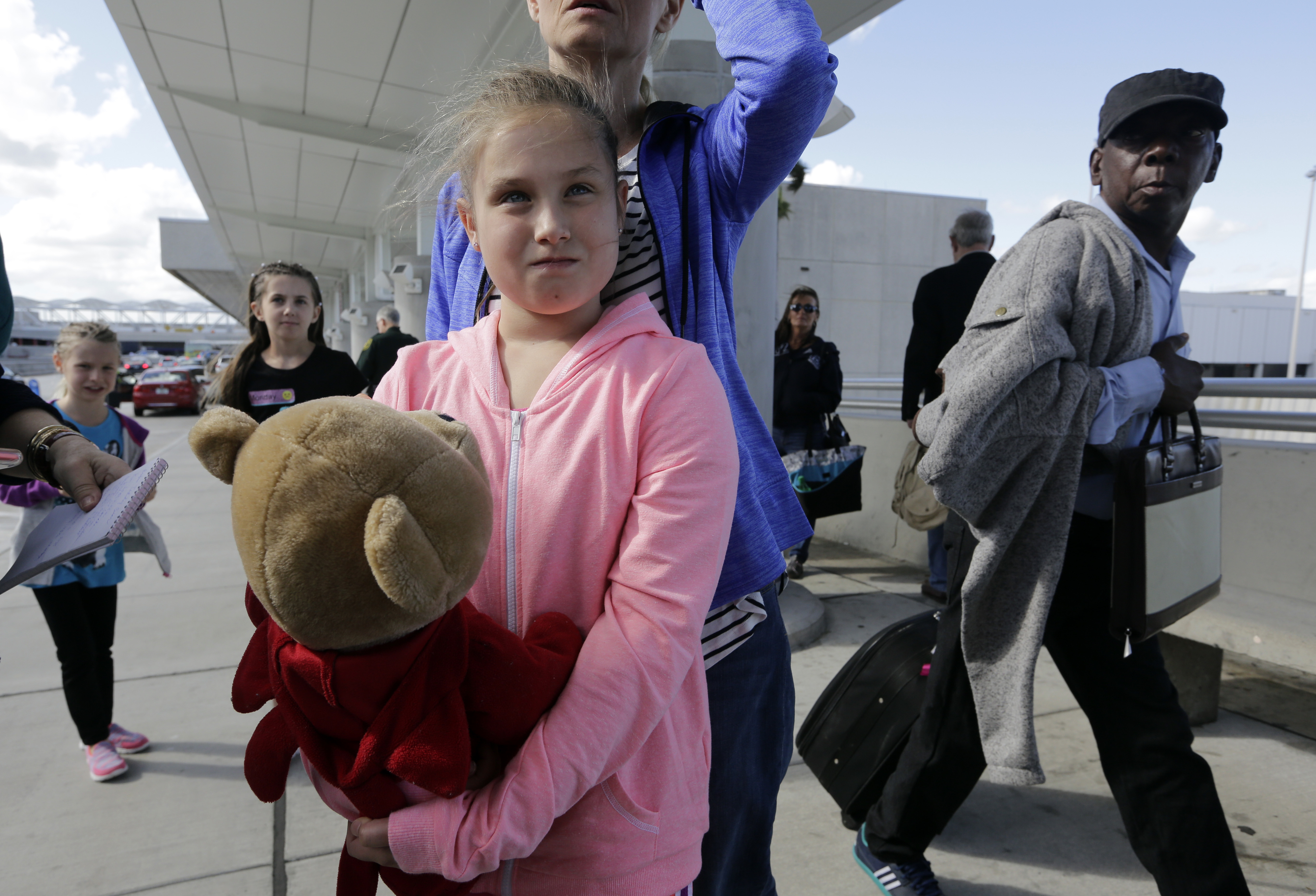 Courtney Gelinas talks with the news media after being reunited with her bear Rufus, at the Fort Lauderdale-Hollywood International Airport, Tuesday, Jan. 10, 2017, in Fort Lauderdale, Fla. Gelinas, of Windsor, Ontario, Canada, was traveling home with her family after a Caribbean cruise. They became separated from their belongings as they fled during last week's shooting at the airport in which five people were killed. (AP Photo/Lynne Sladky)