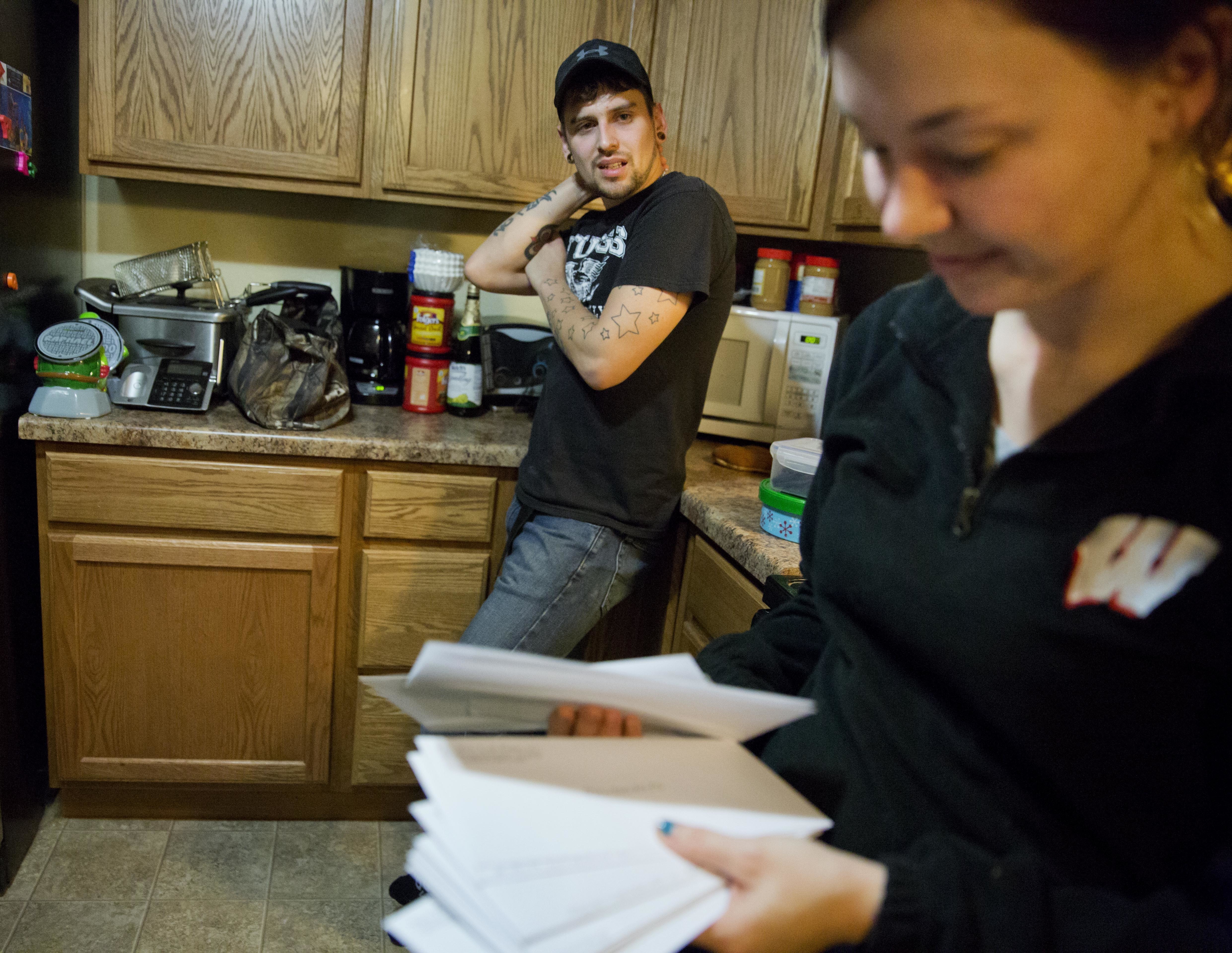 Kreig Holt, left, looks on as his wife, Lydia, flips through envelopes, each containing money for the each of the monthly bills they have to pay, as they stand in their kitchen in Wauzeka, Wis. They both earn about $10 an hour and, with two kids, there's always one or two they have to skip. She did the math; at this rate, they'll be paying these same bills for 87 years. In 2012, Lydia Holt voted for Barack Obama because he promised her change, but she feels that change hasn't reached her here. So in 2016, she chose Donald Trump. (AP Photo/David Goldman)