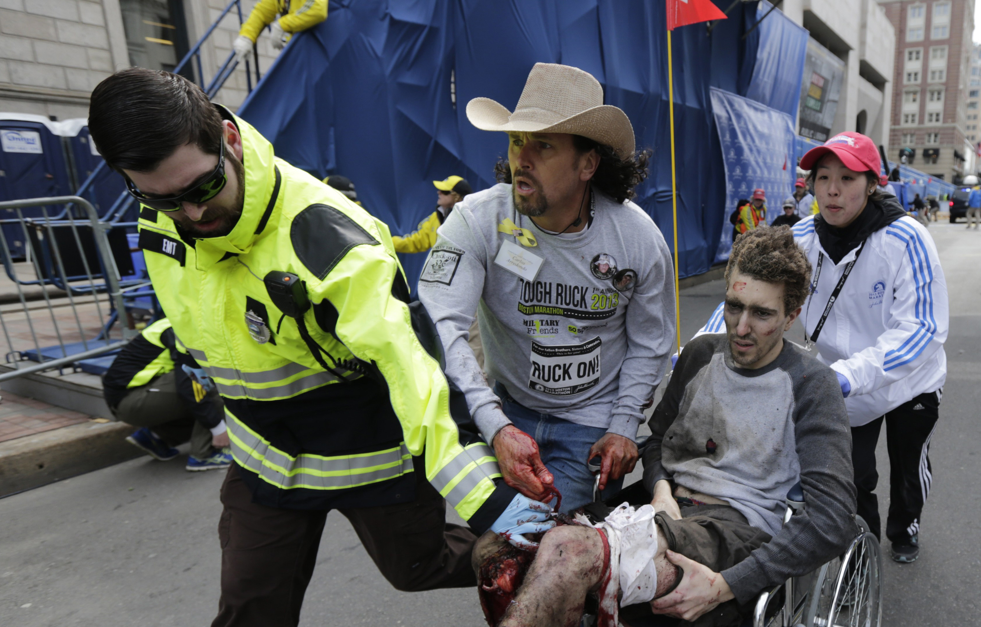 FILE - In this April 15, 2013, file photo, Emergency Medical Services EMT Paul Mitchell, left, Carlos Arredondo, center, and Devin Wang, rear, push Jeff Bauman in a wheelchair after he was injured in one of two explosions near the finish line of the Boston Marathon in Boston. Bauman testified Thursday, March 5, 2015, in the federal death penalty trial of Dzhokhar Tsarnaev in Boston, charged with conspiring with his brother to place twin bombs near the finish line of the race, killing three and injuring 260 people. (AP Photo/Charles Krupa, File)