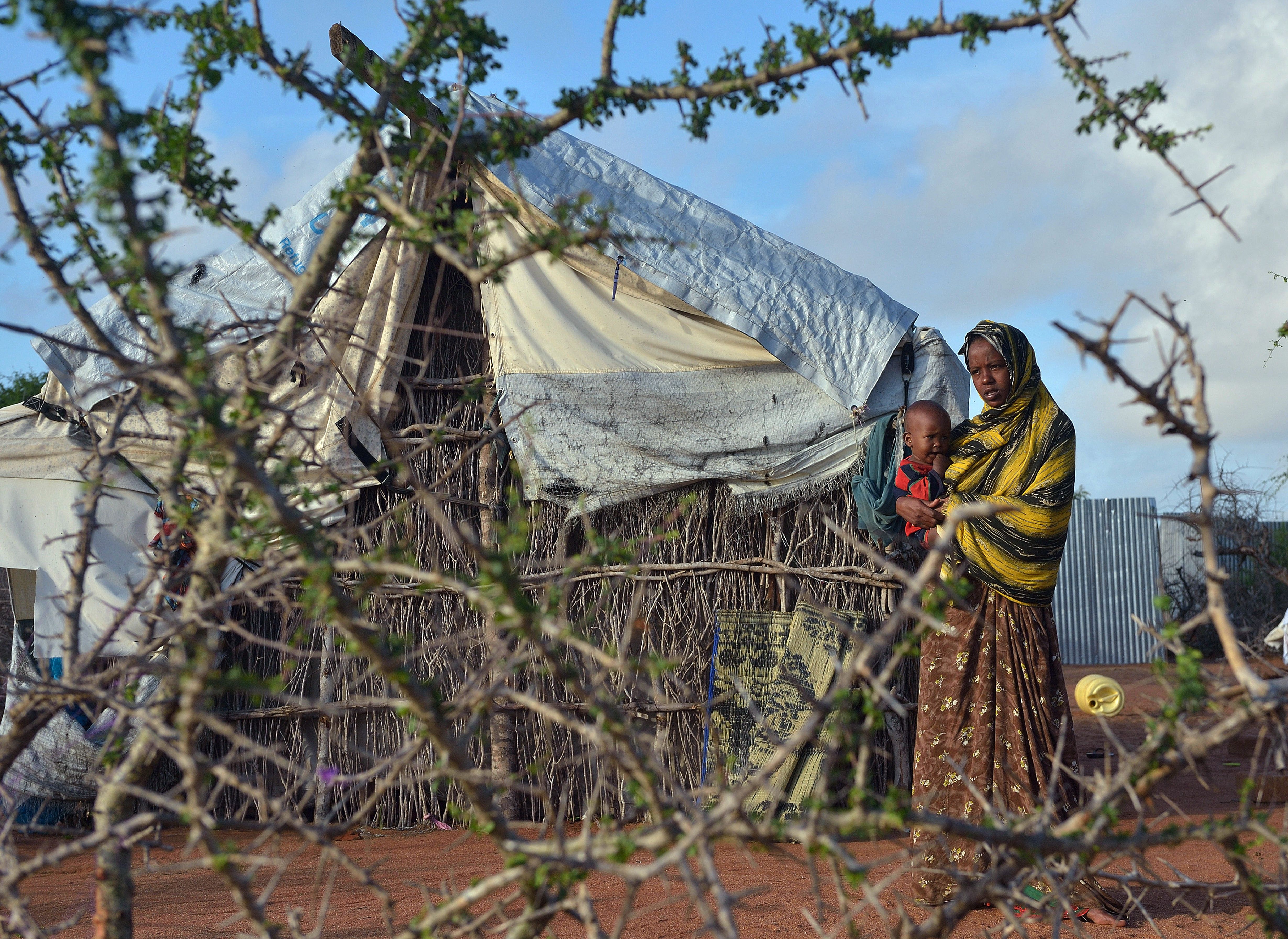 A Somali refugee woman with her child stand in their compound at Hagadera sector of the Dadaab refugee camp, north of the Kenyan capital Nairobi. Photo: Tony Karuma/AFP/Getty Images.