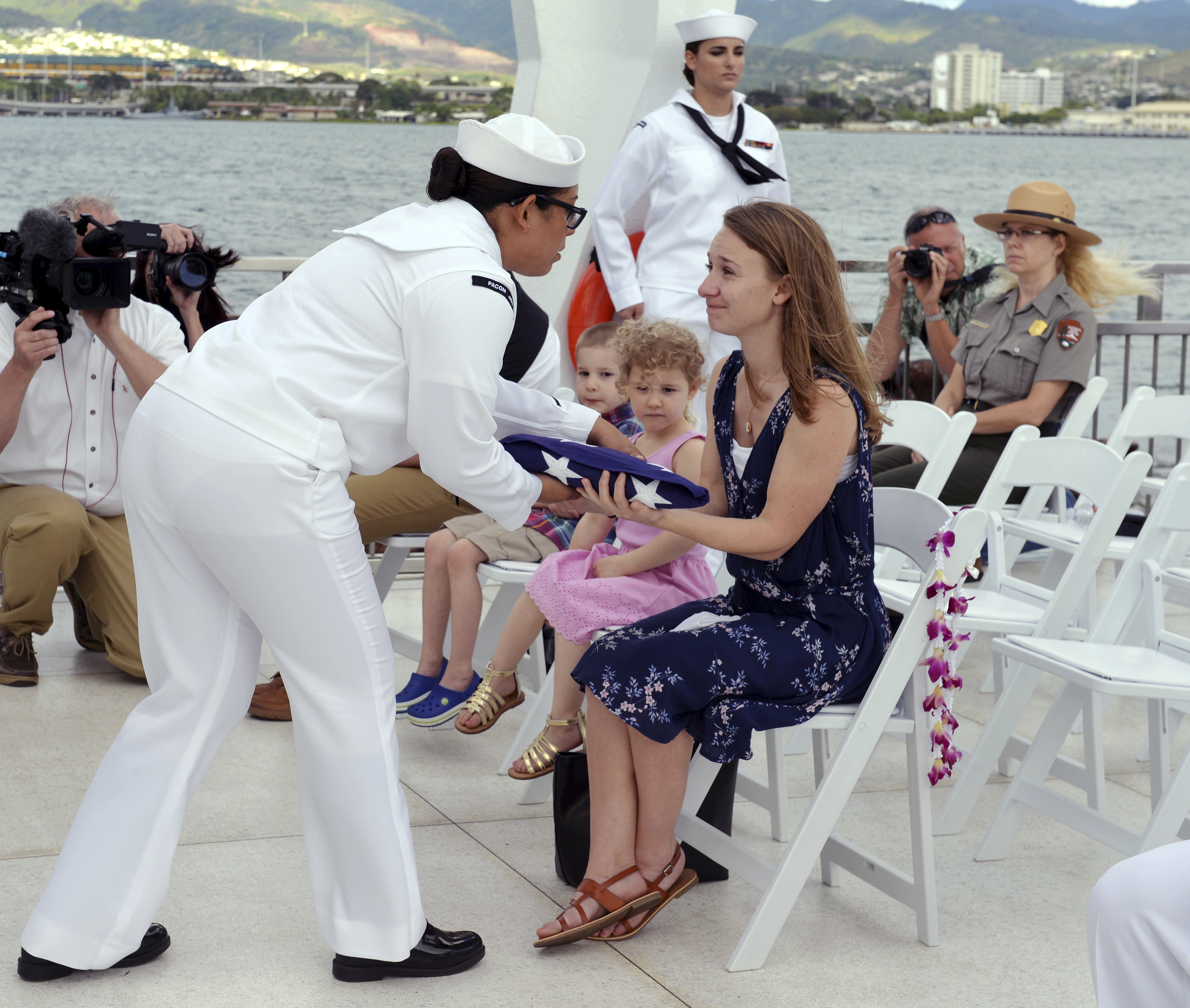 In this Saturday, April 15, 2017 photo released by Pacific Historic Parks, Jessica Marino, center, granddaughter of Raymond Haerry, receives the U.S. flag from the U.S. Navy during a ceremony at the USS Arizona Memorial in Honolulu. (Elaine Simon/Pacific Historic Parks via AP)