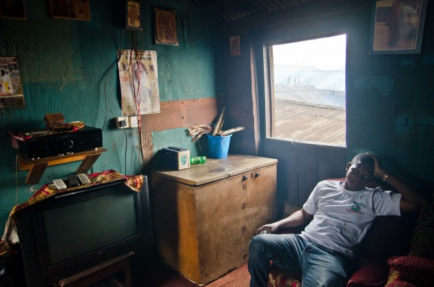 Noah Shemede is the head teacher of Whanyinna Nursery and Primary School in Makoko. Here, he sits in a community leader's home outfitted with modern amenities like television and a stereo. (MPR Photo/Nate Minor)